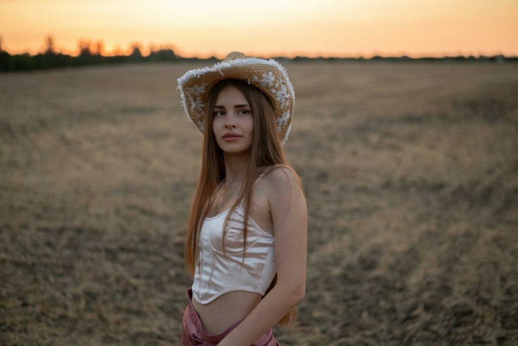 A woman standing in a field wearing a hat